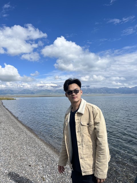 Yuan Zhuang standing by a lake with mountains in the background